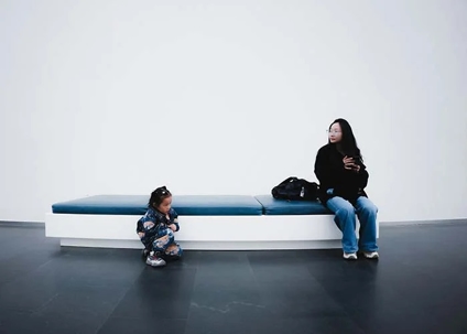 mom sitting on bench and child sitting far away