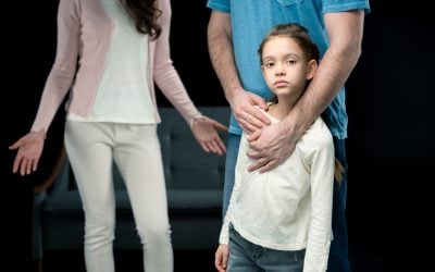 father hugging daughter with mother behind.