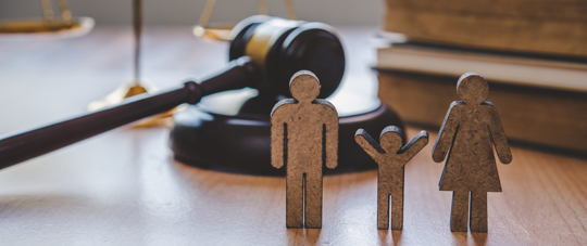 wooden family figurines with a gavel behind it.